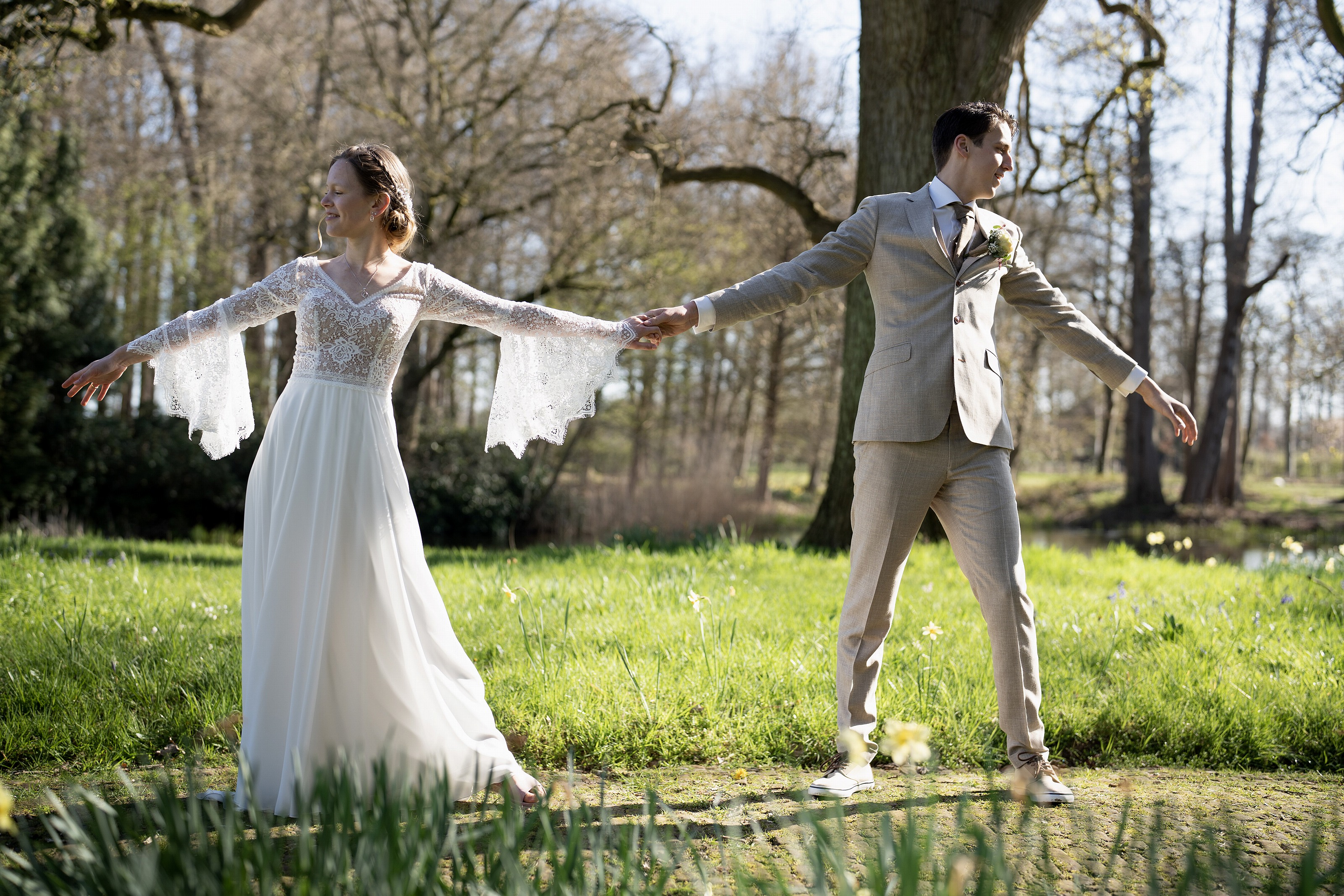 Bruidspaar draait hand in hand tussen narcissen in het park